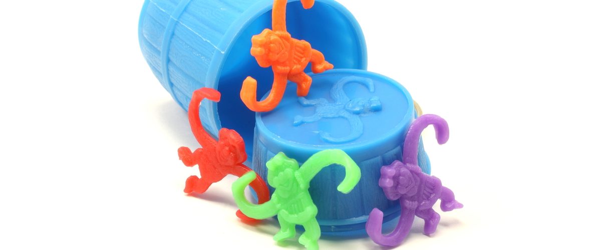 Red orange purple and green monkeys having fun spilling out of a blue barrel.