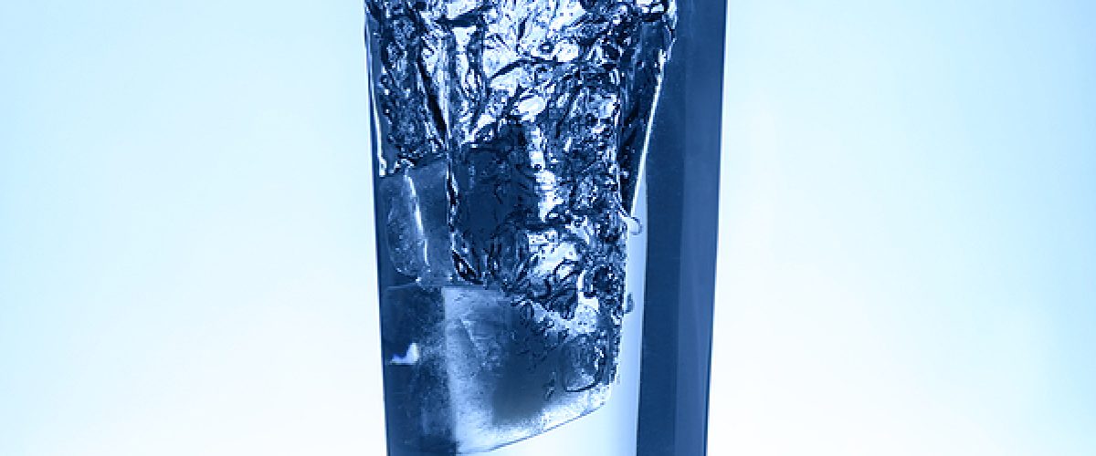 Natural Water Splash in A Glass Over Light Blue Background
