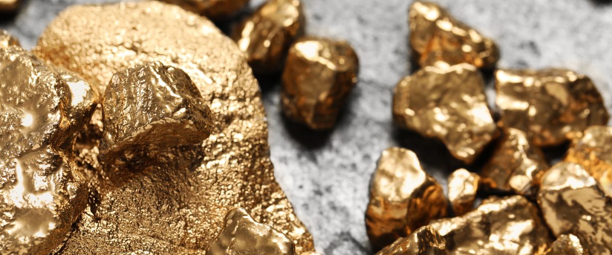 Pile of shiny gold nuggets on grey table, closeup